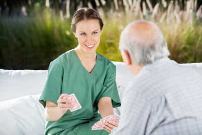 caregiver and senior man playing cards